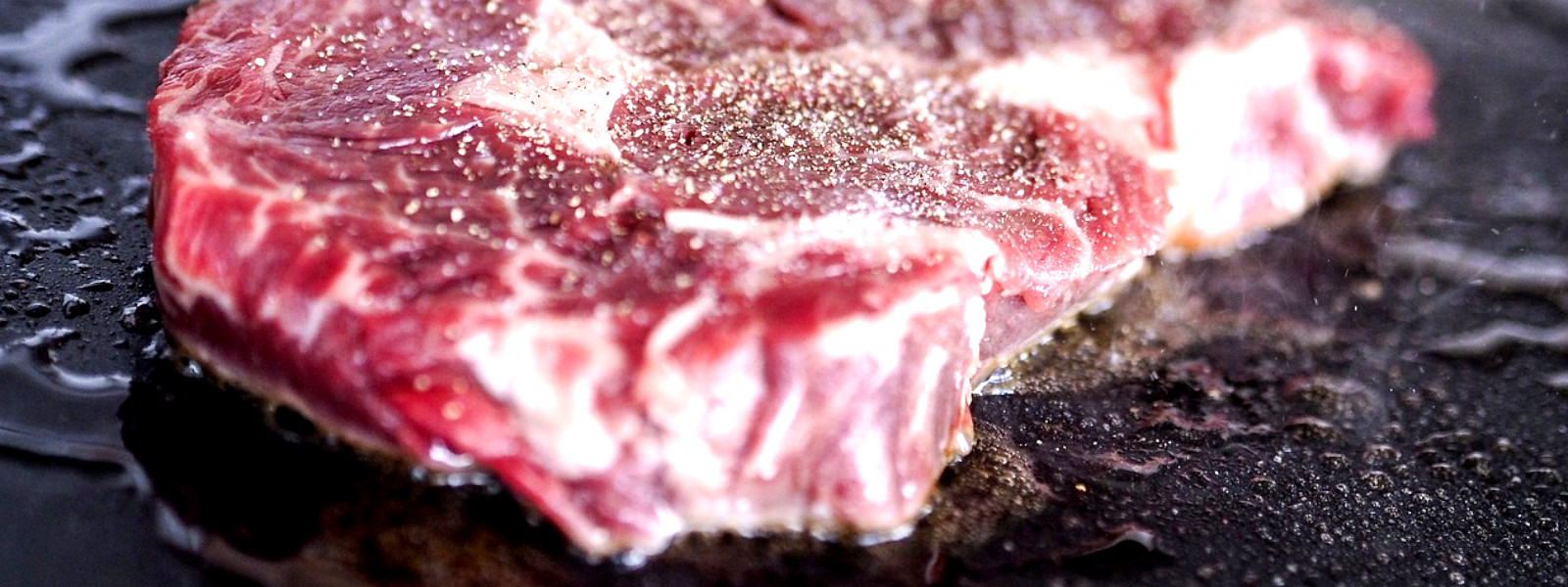 A Imagem mostra um close de uma carne para bife na chapa