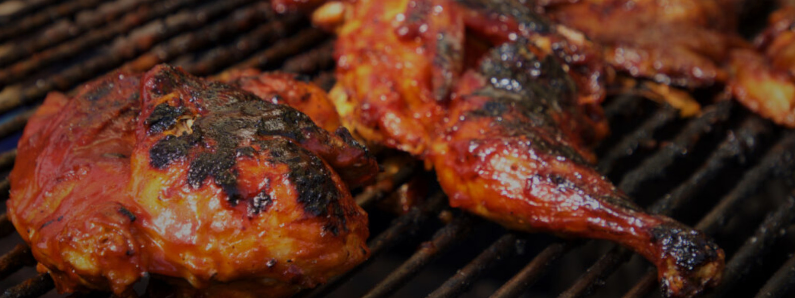 A imagem mostra uma churrasqueira com sobrecoxa temperada