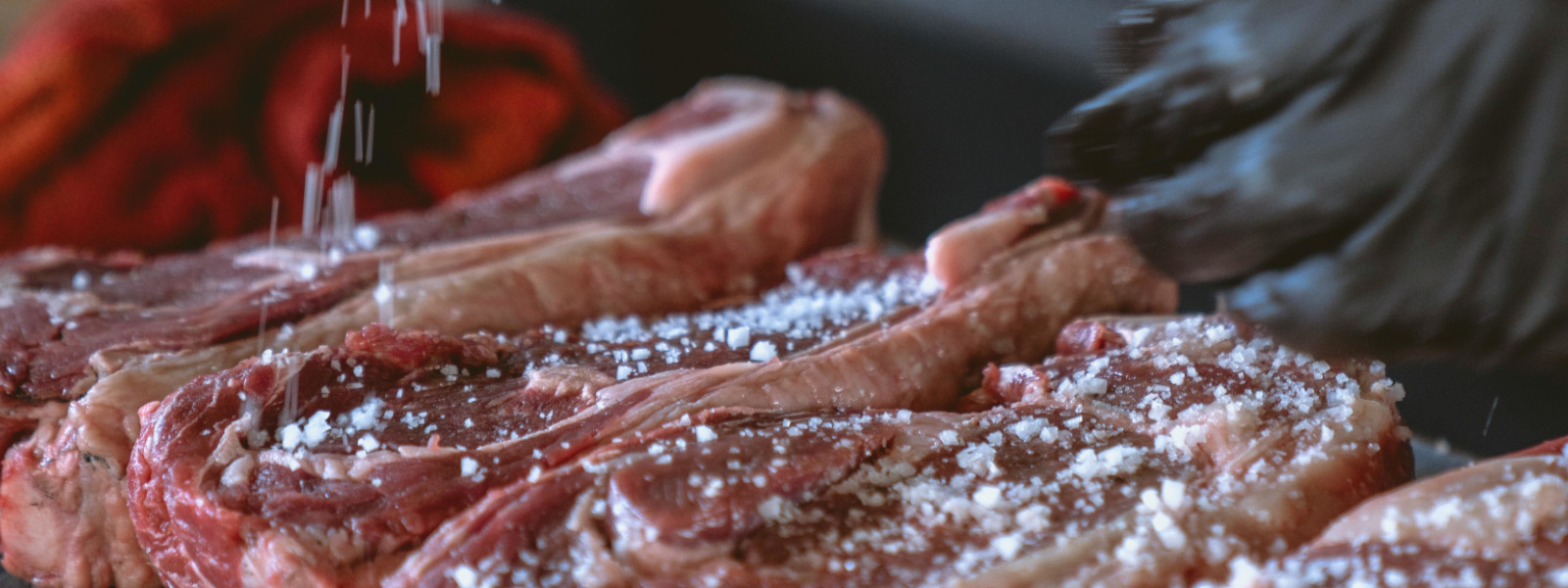 A imagem mostra steaks sendo banhados com tempero de churrasco