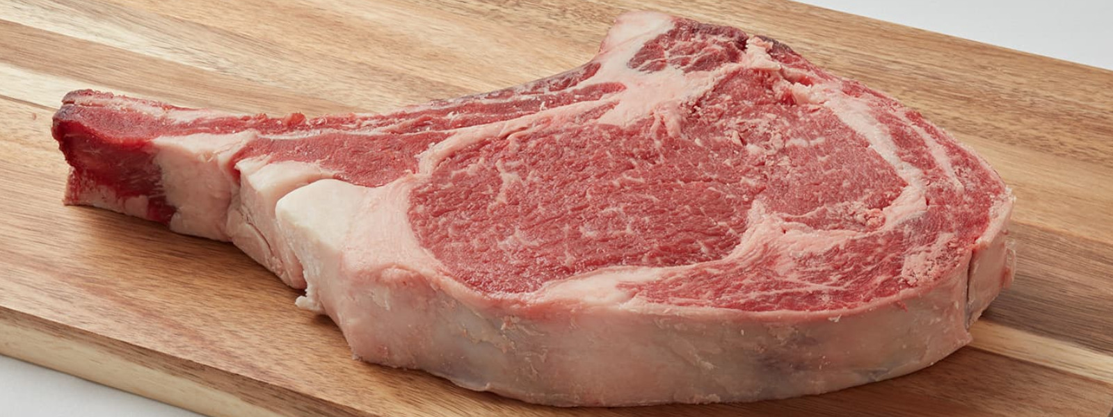 A imagem mostra uma bisteca ou chuleta sobre uma tábua de corte