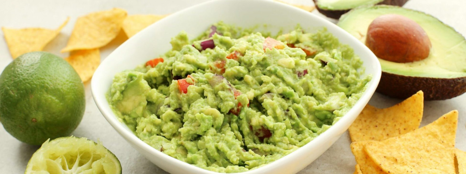 A imagem mostra uma tigela de guacamole com chips de banana da terra